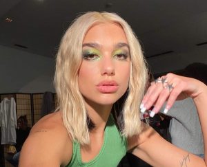 Sängerin Dua Lipa mit blonden Haaren und einem auffälligen grünen Make-Up-Look.